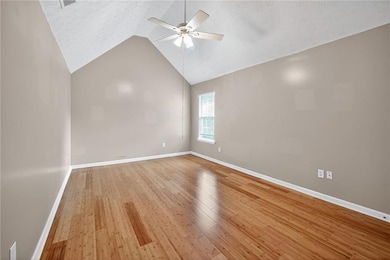 Unfurnished room featuring lofted ceiling, hardwood / wood-style flooring, a textured ceiling, and a ceiling fan