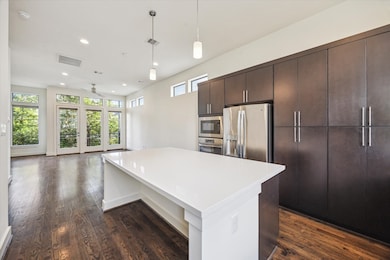 The kitchen is well-lit with pendant lights and na