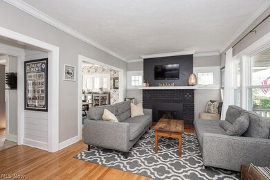 Living room featuring crown molding, light wood-type flooring, and a brick fireplace
