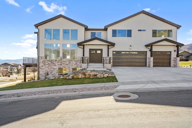 Contemporary house with a mountain view, an attached garage, concrete driveway, and stone siding