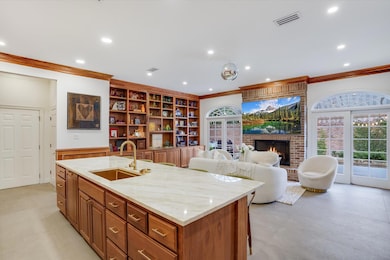 Kitchen with visible vents, an island with sink, ornamental molding, a fireplace, and a sink