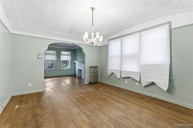 dining area featuring a chandelier, arched walkways, a textured ceiling, hardwood / wood-style flooring, and a brick fireplace