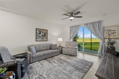Living room with light tile patterned floors, ornamental molding, and ceiling fan