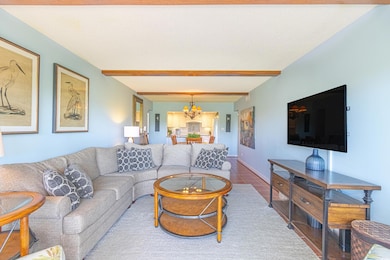 Living area featuring baseboards, beam ceiling, an