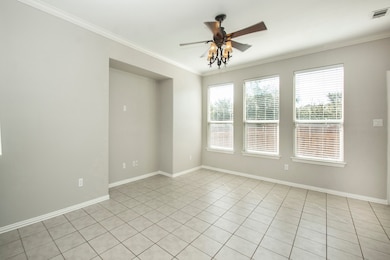 Spare room with crown molding, light tile patterned floors, and ceiling fan