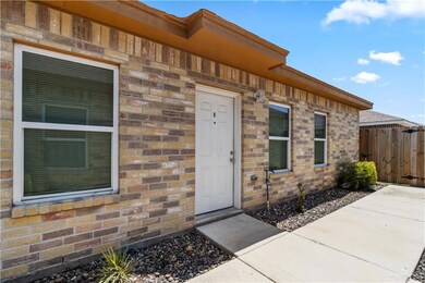 Property entrance featuring brick siding, fence, and a patio