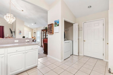 Kitchen with vaulted ceiling, white cabinets, light countertops, light tile patterned flooring, and recessed lighting