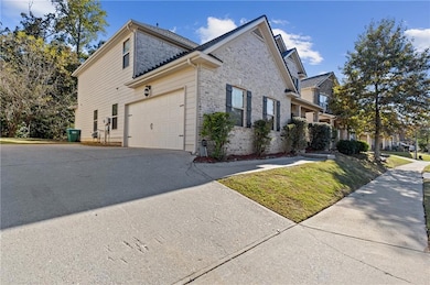 View of side of home featuring brick siding, concrete driveway, a yard, and a garage