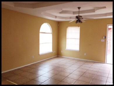 Empty room featuring a raised ceiling, ceiling fan, and light tile patterned floors