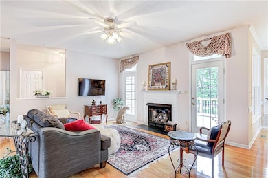 This cozy living room features ceiling fan, wood flooring, and fireplace! Doors lead to rear deck.
