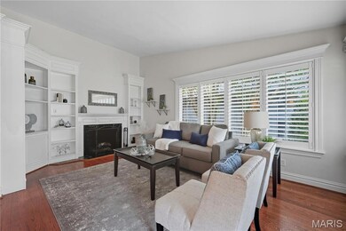 Living room with dark wood finished floors, a fireplace, built in features, and vaulted ceiling