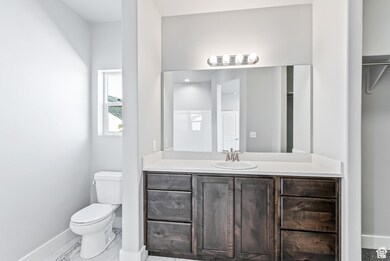 Bathroom with toilet, baseboards, vanity, and marble look tile flooring