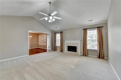 Unfurnished living room featuring carpet flooring, ceiling fan, lofted ceiling, baseboards, and a textured ceiling