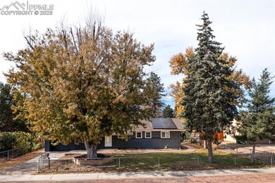 View of front of house with a fenced front yard, brick siding, roof mounted solar panels, and concrete driveway