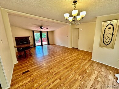 Unfurnished living room with ceiling fan with notable chandelier, light wood-type flooring, and a textured ceiling
