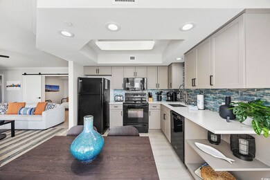 Kitchen with backsplash, sink, light wood-type flooring, gray cabinetry, and black appliances