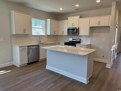 Kitchen featuring white cabinetry, a sink, stainle