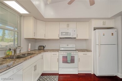 Kitchen with white cabinetry, white appliances, li