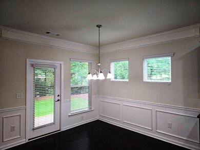 Unfurnished dining area featuring a chandelier, wainscoting, crown molding, and a decorative wall