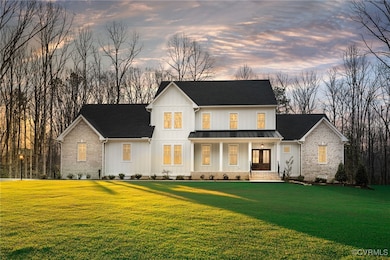 View of front of property with a lawn, metal roof, a standing seam roof, board and batten siding, and brick siding