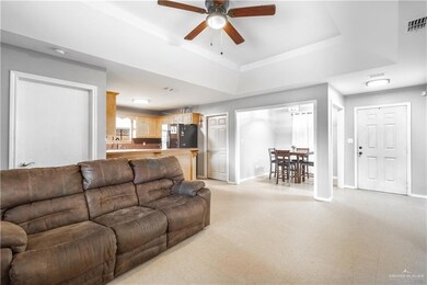 Tiled living room featuring sink, ceiling fan, and a raised ceiling