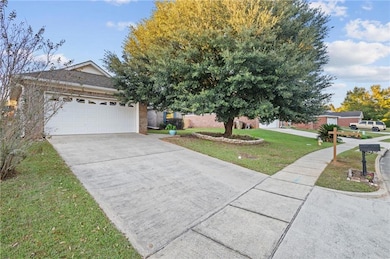 View of front facade with a front yard, driveway, brick siding, and a garage