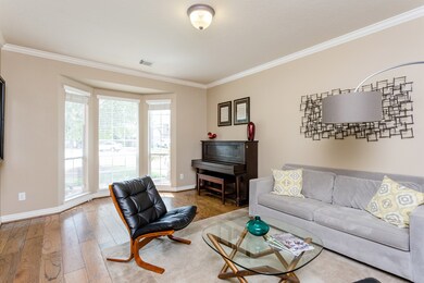 The formal living room features beautiful hardwood floors, custom paint, and large bay windows, a perfect place to host and welcome family and guests.