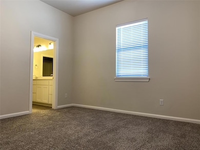 Unfurnished bedroom featuring dark carpet and connected bathroom