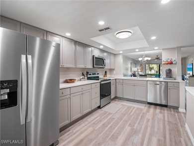 Kitchen with gray cabinets, a raised ceiling, stai