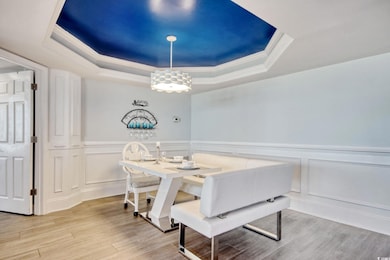 Dining space with crown molding, a tray ceiling, and light hardwood / wood-style flooring