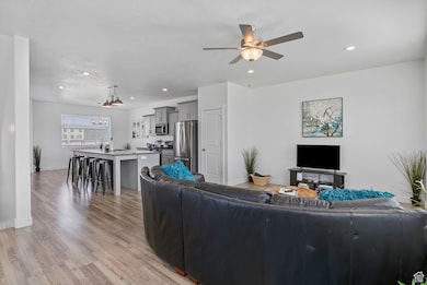 Living area with light wood-style flooring, recessed lighting, a chandelier, and ceiling fan