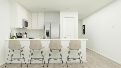 Kitchen featuring appliances with stainless steel finishes, white cabinetry, light wood-type flooring, and a breakfast bar area