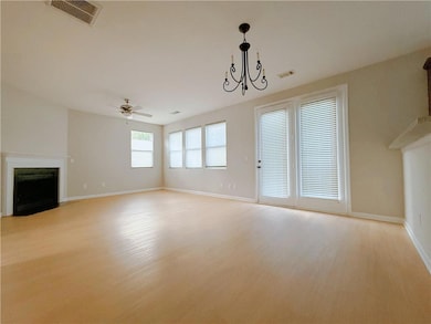 Unfurnished living room featuring a fireplace with flush hearth, light wood-style flooring, a chandelier, and ceiling fan