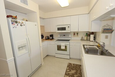 Kitchen with white appliances, light countertops, white cabinetry, and light tile patterned floors