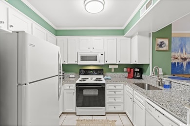 Kitchen with white appliances, a sink, white cabinets, ornamental molding, and light stone countertops