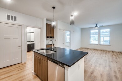 Kitchen featuring dark countertops, dishwasher, light wood-style flooring, and brown cabinets