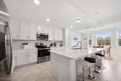 Kitchen with pendant lighting, stainless steel appliances, an island with sink, white cabinetry, and a breakfast bar