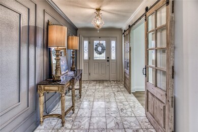 Entryway with ornamental molding, a chandelier, a barn door, and a textured ceiling