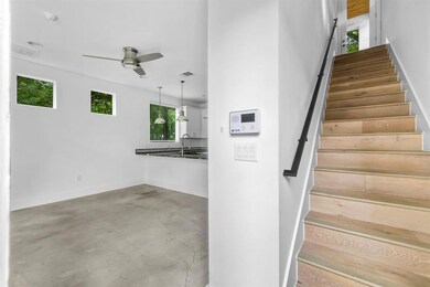 Stairway with ceiling fan, concrete floors, and b