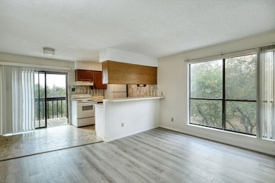 Kitchen featuring brown cabinetry, white appliances, light countertops, a peninsula, and tasteful backsplash