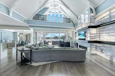 Living area featuring high vaulted ceiling, wood finished floors, a large fireplace, and a chandelier