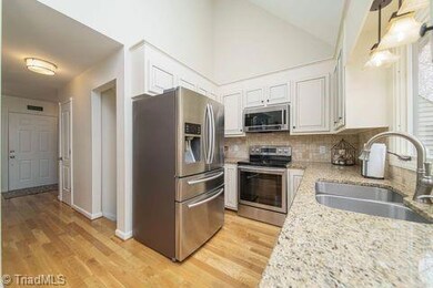 Kitchen with granite countertops, ss appliances, tile backsplash, hardwood floors.