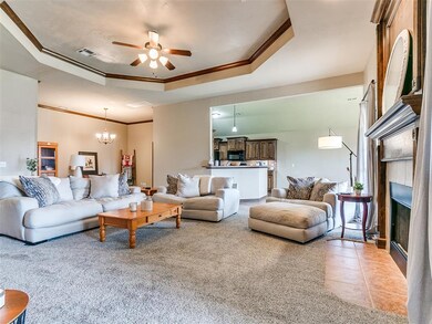 living room with ceiling fan, a tray ceiling, a ti