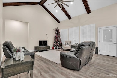 Living room with high vaulted ceiling, light wood-type flooring, ceiling fan, and beamed ceiling