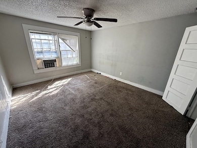 Carpeted spare room featuring a textured ceiling and a ceiling fan