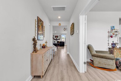 Corridor featuring visible vents, baseboards, and light wood finished floors