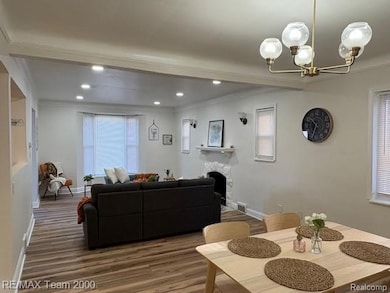 Dining area featuring crown molding, wood finished floors, plenty of natural light, a fireplace, and a chandelier