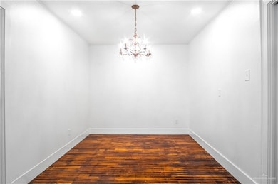 Spare room featuring dark wood-type flooring, crown molding, and a chandelier