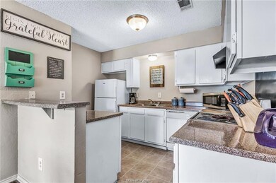 Kitchen featuring white cabinetry, sink, kitchen peninsula, a textured ceiling, and white appliances
