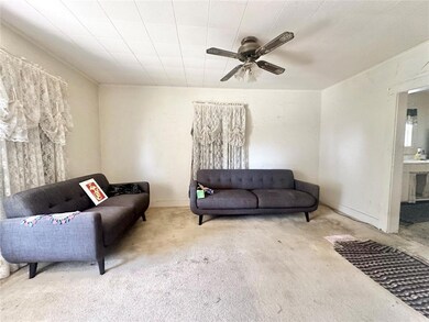 Living room with ceiling fan and light carpet